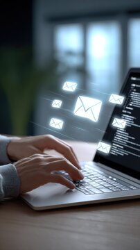 Modern workspace with a person typing on a laptop computer sending and receiving digital email messages with glowing email icons and screens