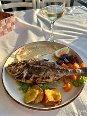 Fresh seafood fish dinner with vegetables and wine, local food in Albania