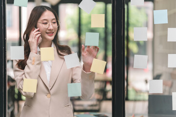 Professional woman engages in creative brainstorming while using smartphone in modern office environment