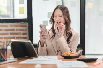 Professional woman engages with smartphone while enjoying snacks in a modern workspace environment