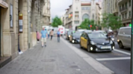 Defocused street view in barcelona, spain, showcasing a blurred scene with people and taxis along the sidewalk.
