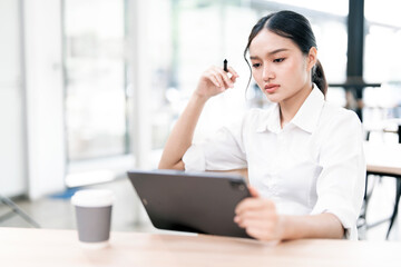 Stressed businesswoman holding digital tablet, sitting at desk and  look worried about her job.