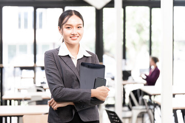 Portrait of happy businesswoman with touchpad in office looking at camera.