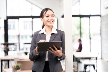 Portrait of happy businesswoman with touchpad in office looking away outside