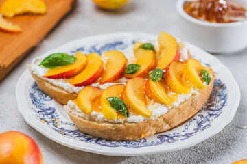 Bruschetta with ricotta cheese, sliced nectarines, basil and honey on a plate