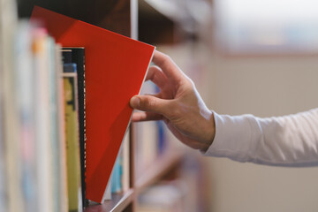 right hand choosing and picking book in public library.
