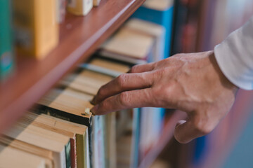 right hand choosing and picking book in public library.