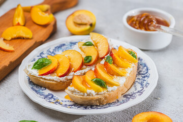 Bruschetta with ricotta cheese, sliced nectarines, basil and honey on a plate