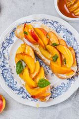 Bruschetta with ricotta cheese, sliced nectarines, basil and honey on a plate