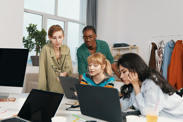 Young adult woman coworkers collaborating in modern workplace, socializing and working together,...