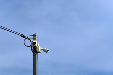 A high-angle surveillance camera mounted on a steel pole contrasts against the backdrop of a clear...