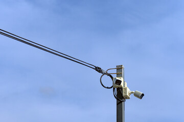 A high-angle surveillance camera mounted on a steel pole contrasts against the backdrop of a clear...