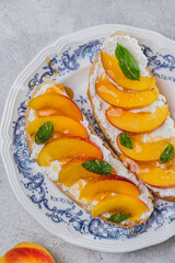 Bruschetta with ricotta cheese, sliced nectarines, basil and honey on a plate