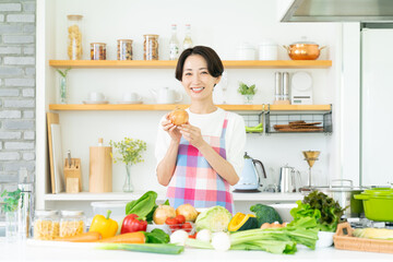 キッチンに立つエプロン姿のミドル女性