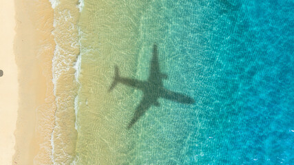 Aerial view of shadow passenger plane silhouette and sandy beach blue sea with waves at sea beach...