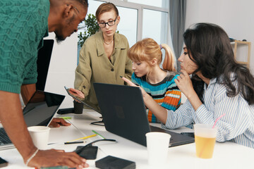 Fototapeta premium Young adult colleagues working together in a modern workplace, focusing on collaboration and socializing among Gen Z coworkers and friends in a business environment.