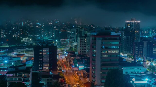 Time-lapse of panoramic night view of clouds covering buildings in the northern part of Quito with car traffic circulating in the streets - Ecuador