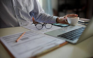 asian businessman have coffee drink while working and meeting online with business group via laptop on desk at home office, working at home concept