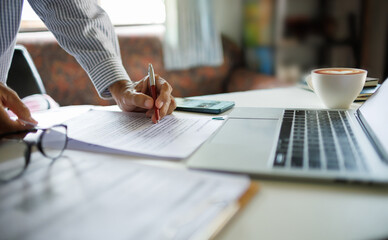 asian businessman standing at desk office checking document report and business contract using laptop working and meeting online