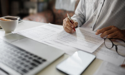asian businessman checking document report and business contract using laptop working at home office, working at home concept