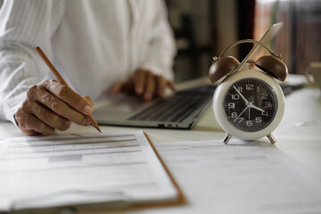asian businessman review business contract and document using laptop working on table before work time end in a day,  time management concept, routine work, office hour