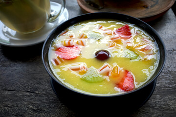 A tropical smoothie bowl with mango, kiwi and strawberry fruits, on an old wooden table