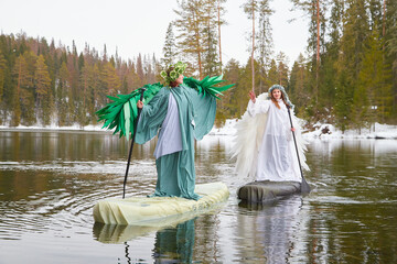Girls in white and green dresses on a lake symbolize the meeting of winter and spring in a magical...