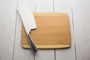 Large knife and chopping board on wooden floor