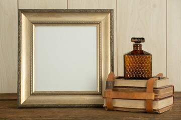 Photo frame, perfume and book stack on table