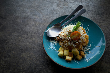 Volcano shaped Spaghetti in blue plate garnished with celery leaves, cheese, biscuits and sliced ​​tomatoes