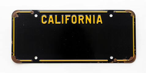 Old California license plate with yellow embossed letters on a black background. Corners show rust, adding a vintage and nostalgic feel