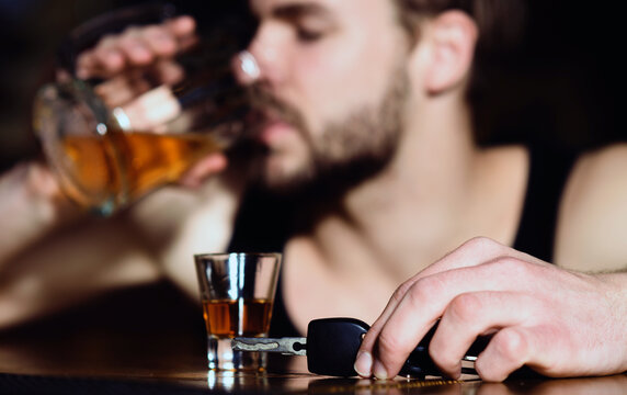 Drunk driver with car key. Alcohol problem. Lonely man drinking before driving vehicle. Drunk driver man with glass of alcohol. Hopeless alcoholic driver.