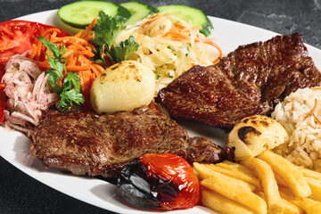 Beef steaks with grilled vegetables, fries and rice, bright rustic overhead plating