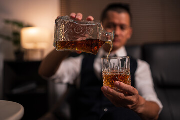 Bartender is pouring whiskey into a glass a customer's glass.	