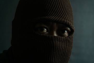 Male subject with brown fabric eye mask fully worn on face, isolated on black, suggesting secrecy,...