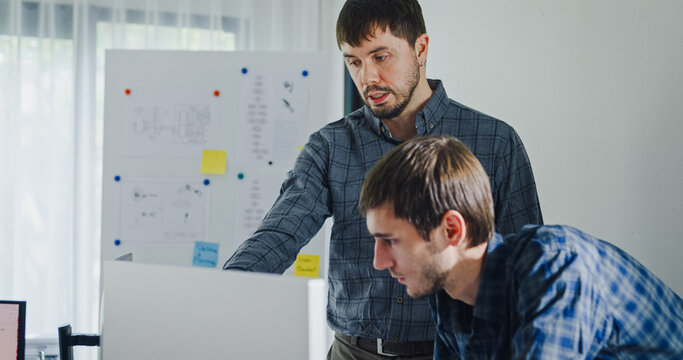 Team adult male engineer collaborate on robotic hand project using AI code solutions machine learning at tech workspace. Artificial intelligence interface, collaboration support prototype development.