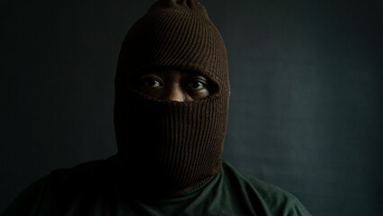 Male subject with brown fabric eye mask fully worn on face, isolated on black, suggesting secrecy,...