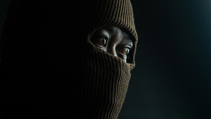 Close-up portrait of man with brown cloth mask covering face except eyes, intense and secretive...