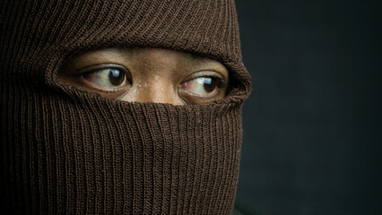 Close-up portrait of man with brown cloth mask covering face except eyes, intense and secretive...