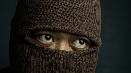 Close-up portrait of man with brown cloth mask covering face except eyes, intense and secretive...