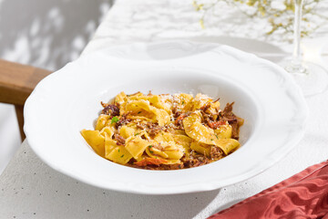 Pappardelle pasta with slow-braised cheek, bright daylight, overhead minimal composition
