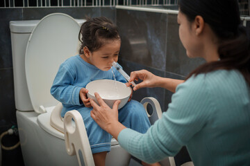 mother making nasal wash for toddler girl with syringe and saline. cleaning nose