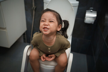 toddler girl sitting on toilet at home and suffering from stomachache and constipation