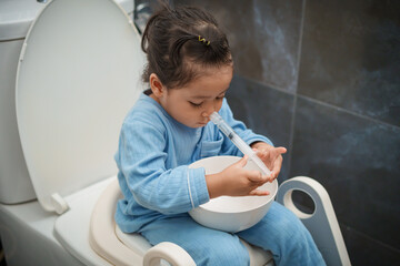 toddler girl washing nasal with syringe and saline by herself. cleaning nose