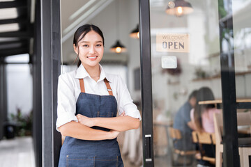 Portrait of smiling waitress standing with arms crossed at her shop