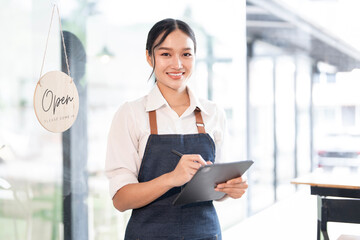 Cheerful  adult waitress holding digital tablet at cafe, smiling to camera
