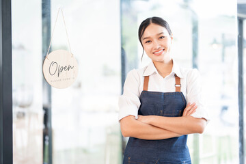 Portrait of smiling waitress standing with arms crossed at her shop