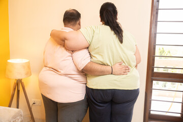 Overweight indian couple standing together. Back view of plus size husband wife bonding. Obesity...