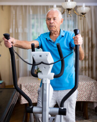 Fit senior man at home doing cardio work out on an elliptical machine