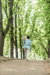 Woman Flowers Park: Girl carries daisies down path in lush green park during daytime.